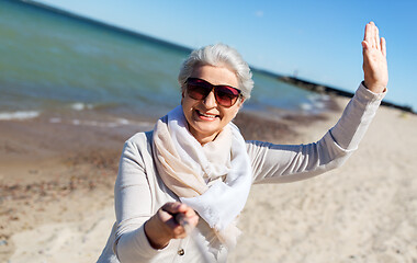 Image showing old woman taking selfie and waving hand on beach