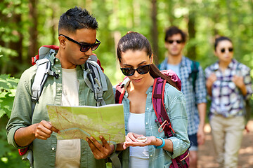 Image showing friends with map and backpacks hiking in forest