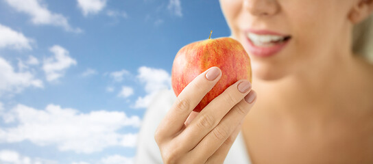 Image showing close up of woman holding ripe red apple over sky