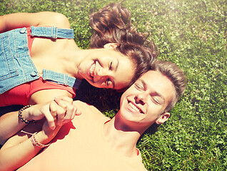 Image showing happy teenage couple lying on grass at summer