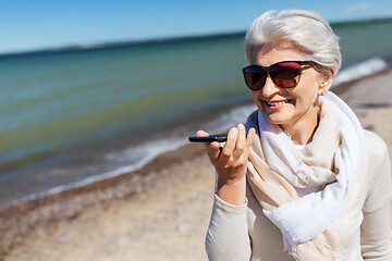 Image showing old woman recording voice by smartphone on beach