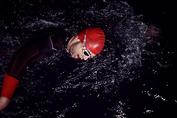 Image showing triathlon athlete swimming in dark night wearing wetsuit