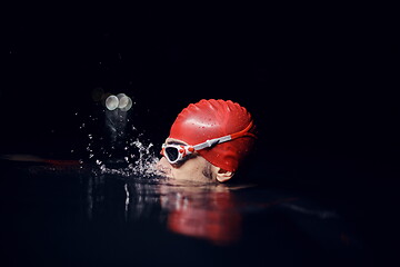 Image showing authentic triathlete swimmer having a break during hard training on night