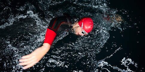 Image showing triathlon athlete swimming in dark night wearing wetsuit