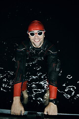 Image showing authentic triathlete swimmer having a break during hard training on night