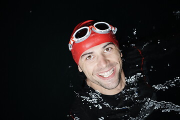 Image showing authentic triathlete swimmer having a break during hard training on night