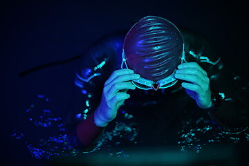 Image showing authentic triathlete swimmer having a break during hard training on night neon gel light