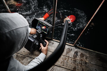 Image showing videographer taking action shot of triathlon swimming athlete at night