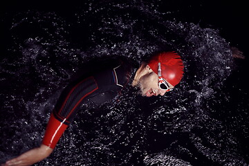 Image showing triathlon athlete swimming in dark night wearing wetsuit