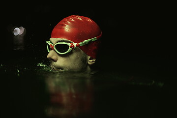 Image showing authentic triathlete swimmer having a break during hard training on night neon gel light