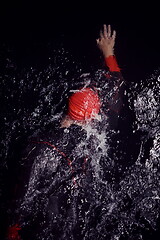 Image showing triathlon athlete swimming in dark night wearing wetsuit