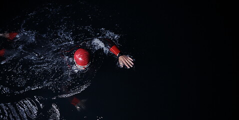 Image showing triathlon athlete swimming in dark night wearing wetsuit