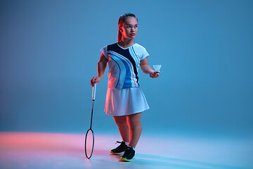 Image showing Beautiful dwarf woman practicing in badminton isolated on blue background in neon light