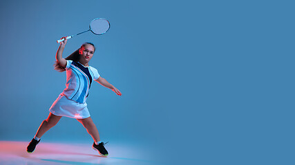 Image showing Beautiful dwarf woman practicing in badminton isolated on blue background in neon light