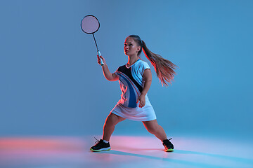 Image showing Beautiful dwarf woman practicing in badminton isolated on blue background in neon light