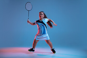 Image showing Beautiful dwarf woman practicing in badminton isolated on blue background in neon light