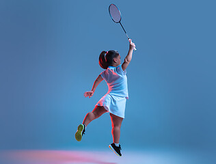 Image showing Beautiful dwarf woman practicing in badminton isolated on blue background in neon light