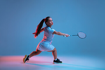 Image showing Beautiful dwarf woman practicing in badminton isolated on blue background in neon light