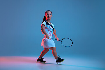 Image showing Beautiful dwarf woman practicing in badminton isolated on blue background in neon light