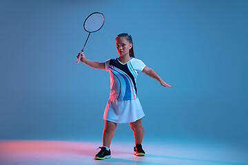 Image showing Beautiful dwarf woman practicing in badminton isolated on blue background in neon light