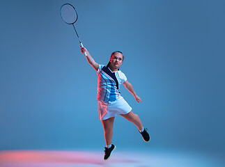 Image showing Beautiful dwarf woman practicing in badminton isolated on blue background in neon light