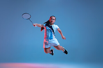 Image showing Beautiful dwarf woman practicing in badminton isolated on blue background in neon light