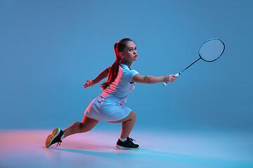 Image showing Beautiful dwarf woman practicing in badminton isolated on blue background in neon light