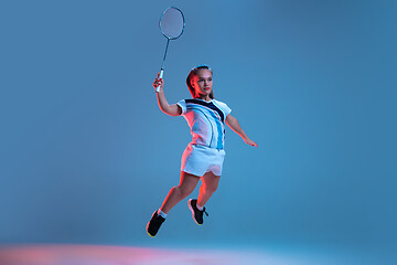 Image showing Beautiful dwarf woman practicing in badminton isolated on blue background in neon light