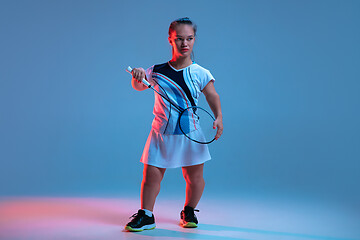 Image showing Beautiful dwarf woman practicing in badminton isolated on blue background in neon light