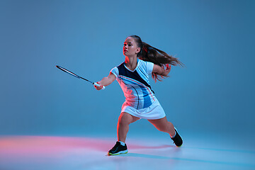 Image showing Beautiful dwarf woman practicing in badminton isolated on blue background in neon light