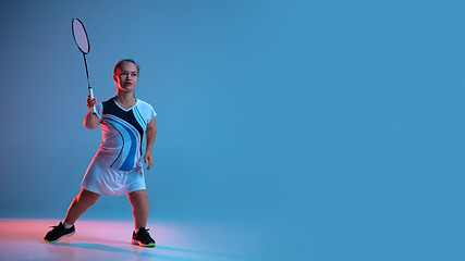 Image showing Beautiful dwarf woman practicing in badminton isolated on blue background in neon light