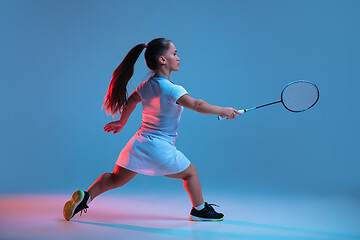 Image showing Beautiful dwarf woman practicing in badminton isolated on blue background in neon light