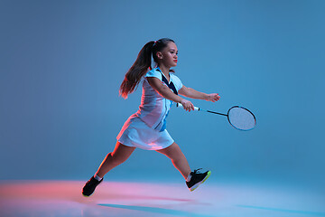 Image showing Beautiful dwarf woman practicing in badminton isolated on blue background in neon light