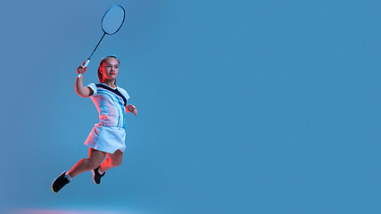 Image showing Beautiful dwarf woman practicing in badminton isolated on blue background in neon light