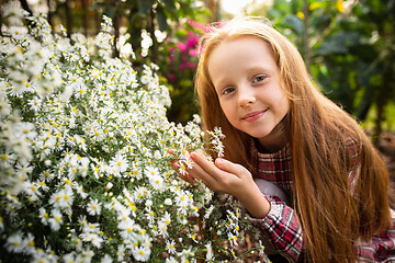 Image showing Happy little girl with flowers in a garden outdoors