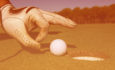 Image showing man\'s hand putting golf ball in hole