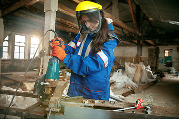 Image showing Woman wearing helmet using male work tools