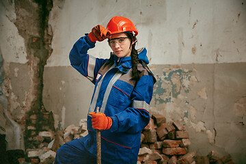 Image showing Woman wearing helmet using male work tools