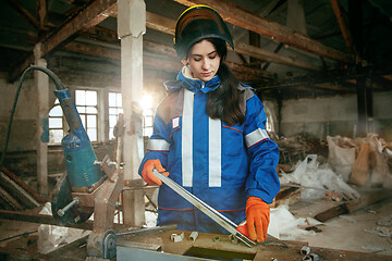 Image showing Woman wearing helmet using male work tools