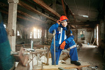 Image showing Woman wearing helmet using male work tools