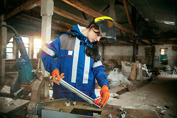 Image showing Woman wearing helmet using male work tools