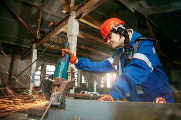 Image showing Woman wearing helmet using male work tools