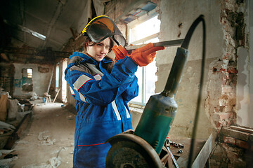 Image showing Woman wearing helmet using male work tools