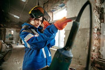 Image showing Woman wearing helmet using male work tools