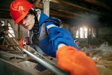 Image showing Woman wearing helmet using male work tools