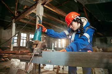 Image showing Woman wearing helmet using male work tools