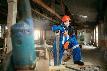 Image showing Woman wearing helmet using male work tools