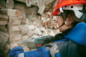 Image showing Woman wearing helmet using male work tools