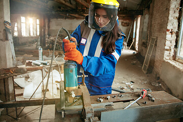 Image showing Woman wearing helmet using male work tools