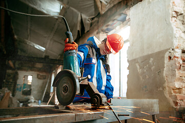 Image showing Woman wearing helmet using male work tools